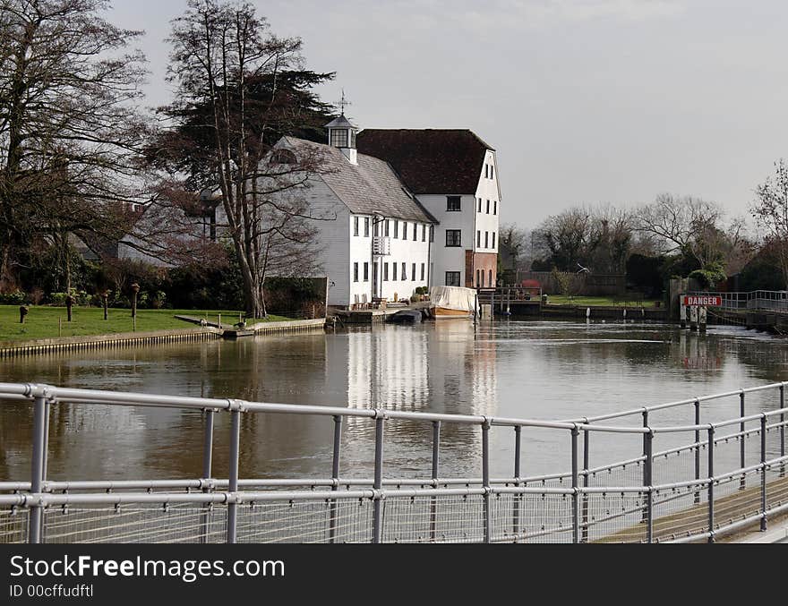 Winter scene of a an Historic Riverside Mill House with Boats moored to the front