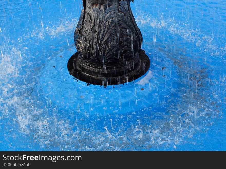 Water splashing around a fountain in a blue pool. Water splashing around a fountain in a blue pool.