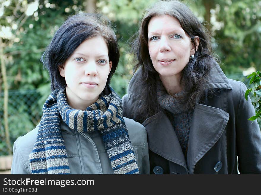 Mother and daughter, outdoor, closed together, close-up, looking interested. Mother and daughter, outdoor, closed together, close-up, looking interested