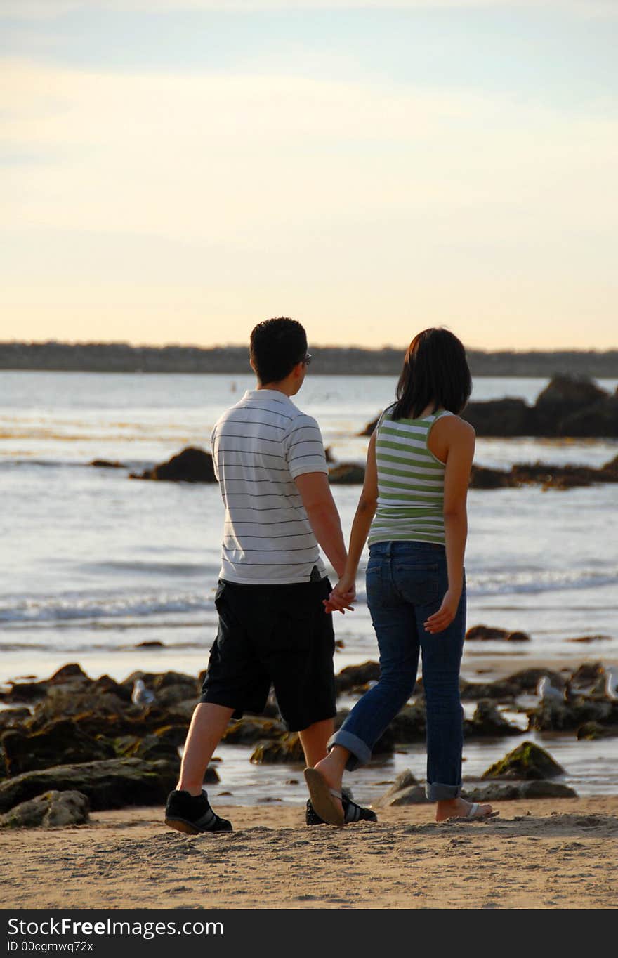 A couple is walking holding hands on the beach. A couple is walking holding hands on the beach