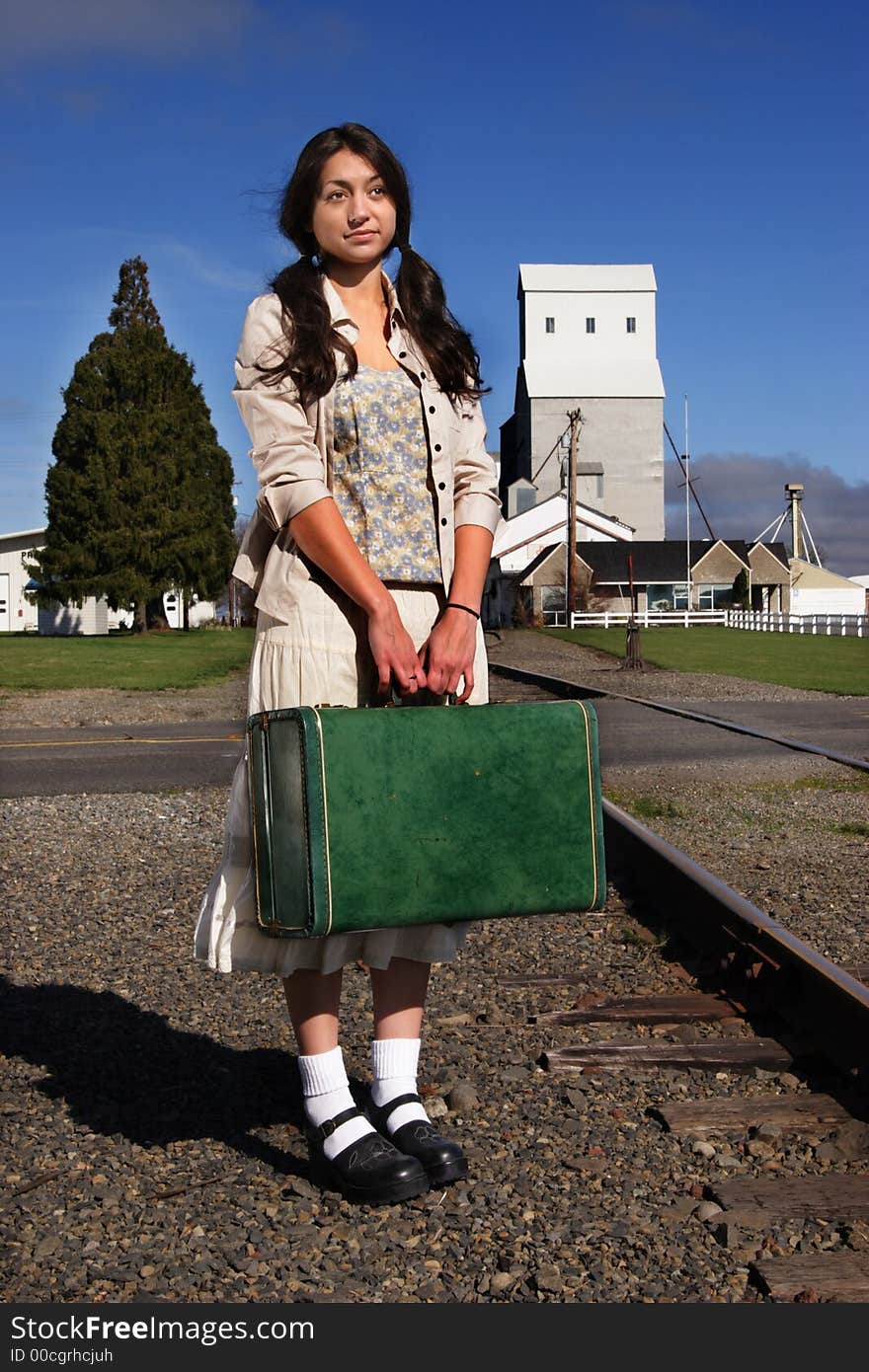 A stock image of a young woman in a rural setting waiting for a train. Suitcase. Portrait. A stock image of a young woman in a rural setting waiting for a train. Suitcase. Portrait.