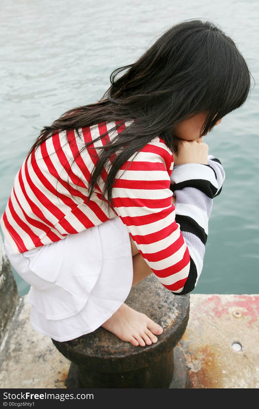 Different colored stripes worn by a young Asian girl squatting. Different colored stripes worn by a young Asian girl squatting