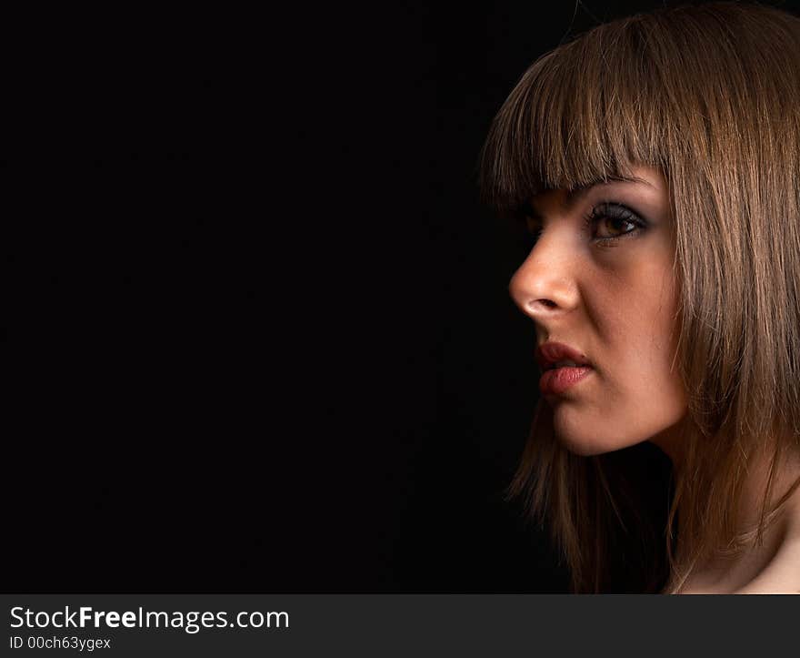 High fashion shoot - young woman over black background with moody light. High fashion shoot - young woman over black background with moody light