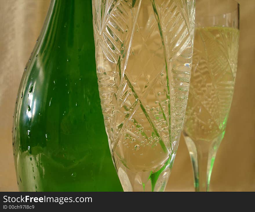 Close-up view of Champagne glasses with bottle on golden background