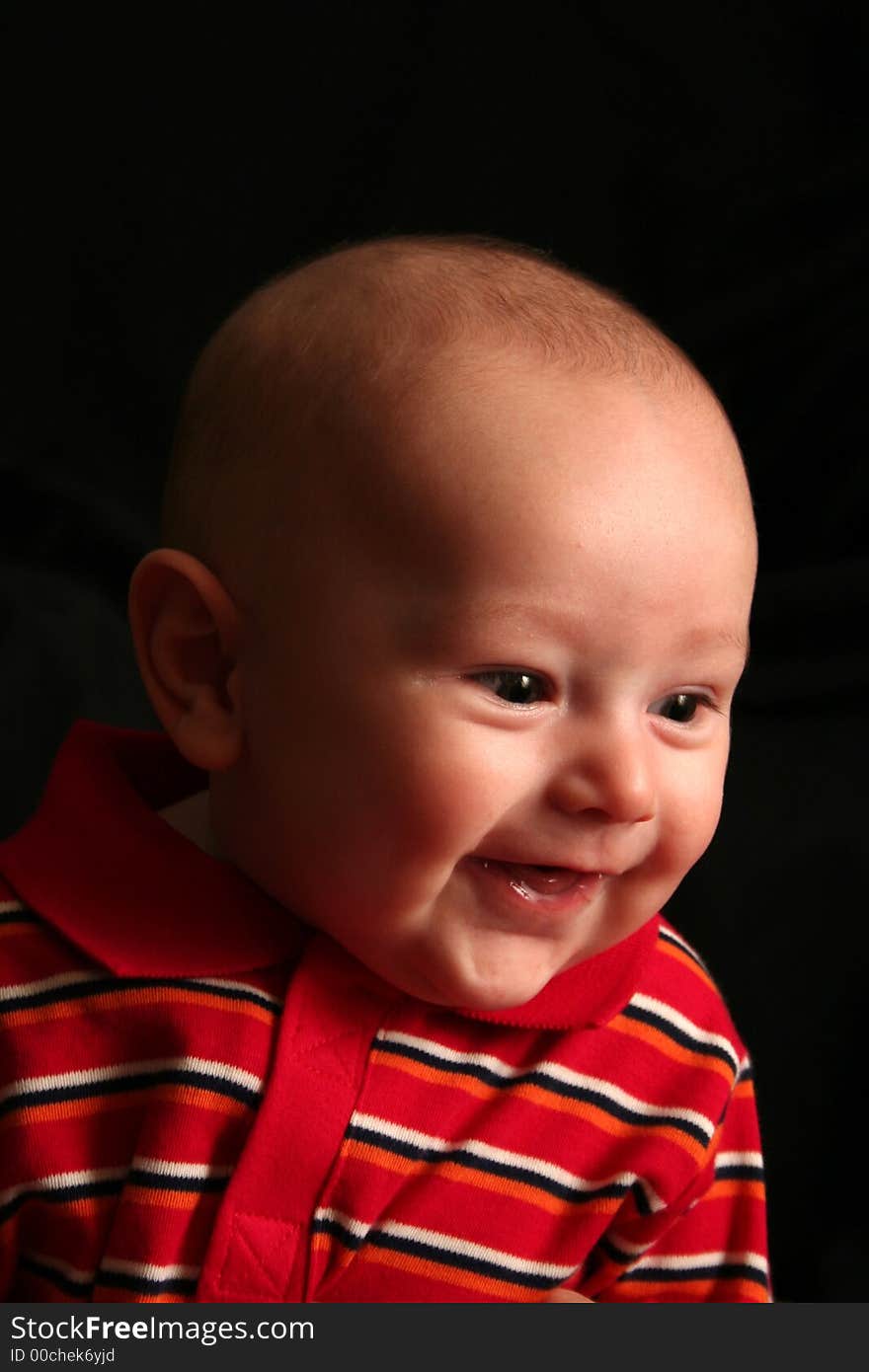 The face of a baby boy posing for the camera on a black background. The face of a baby boy posing for the camera on a black background.