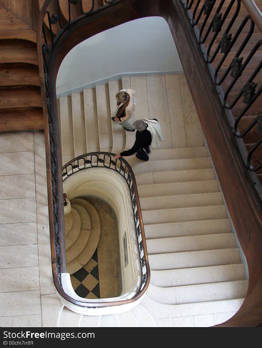 Spiral staircase in France looking down with a couple walking