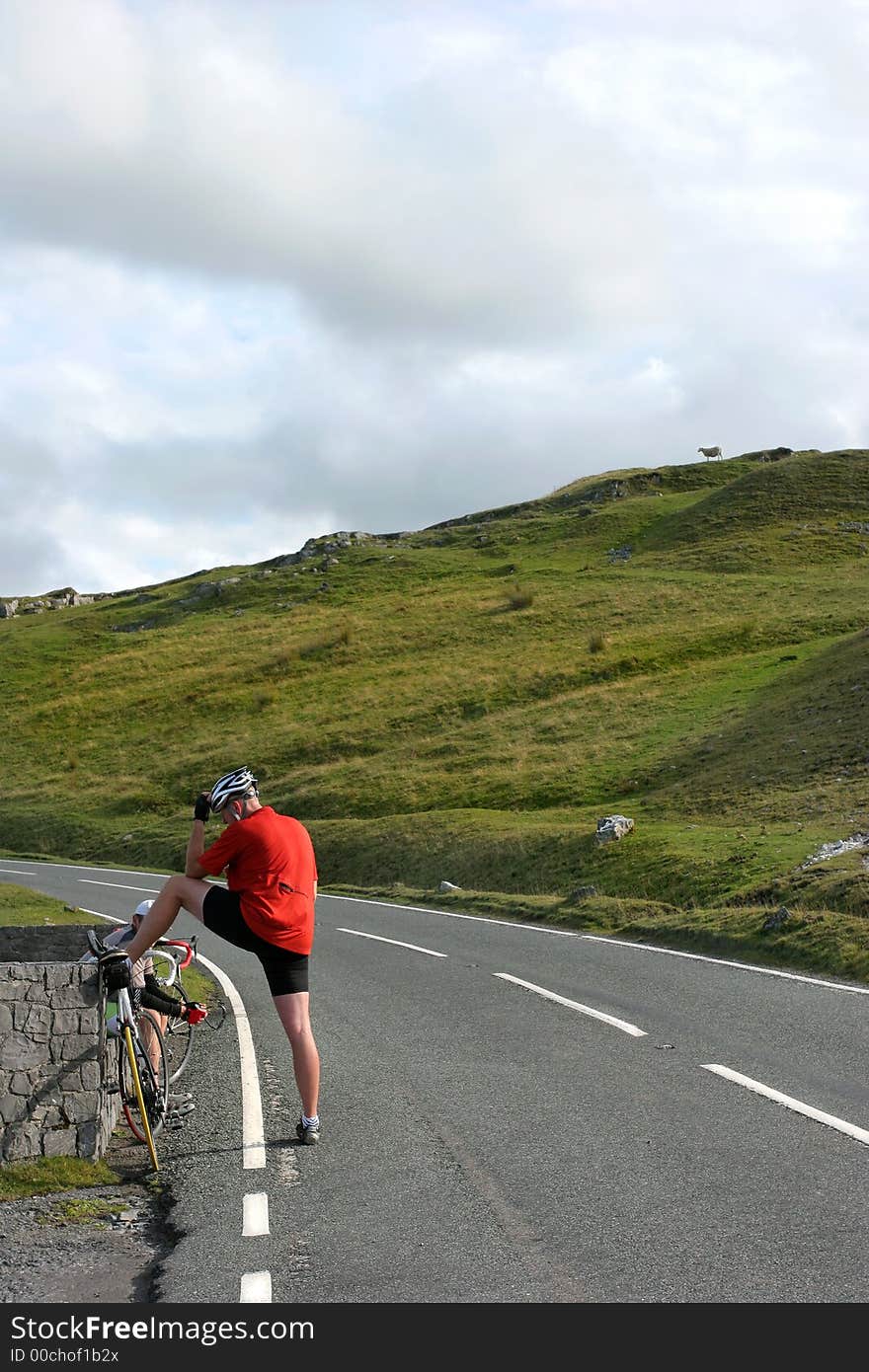 Male cyclist stopping for a rest on an uphill rural mountain road. Male cyclist stopping for a rest on an uphill rural mountain road.