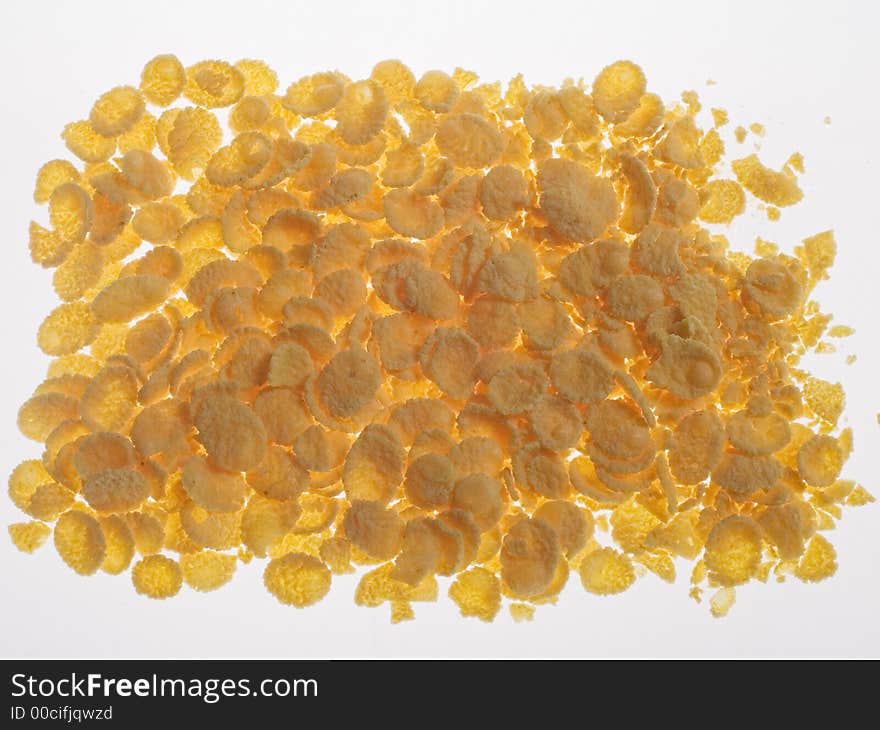 Scattered yellow corn flakes on the white surface