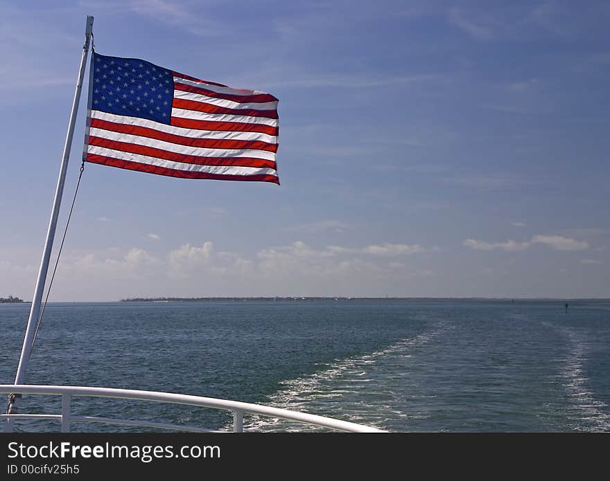 The wake of a speedboat and the north end of Captiva Island - the American Flag waves off the back of the boat. The wake of a speedboat and the north end of Captiva Island - the American Flag waves off the back of the boat