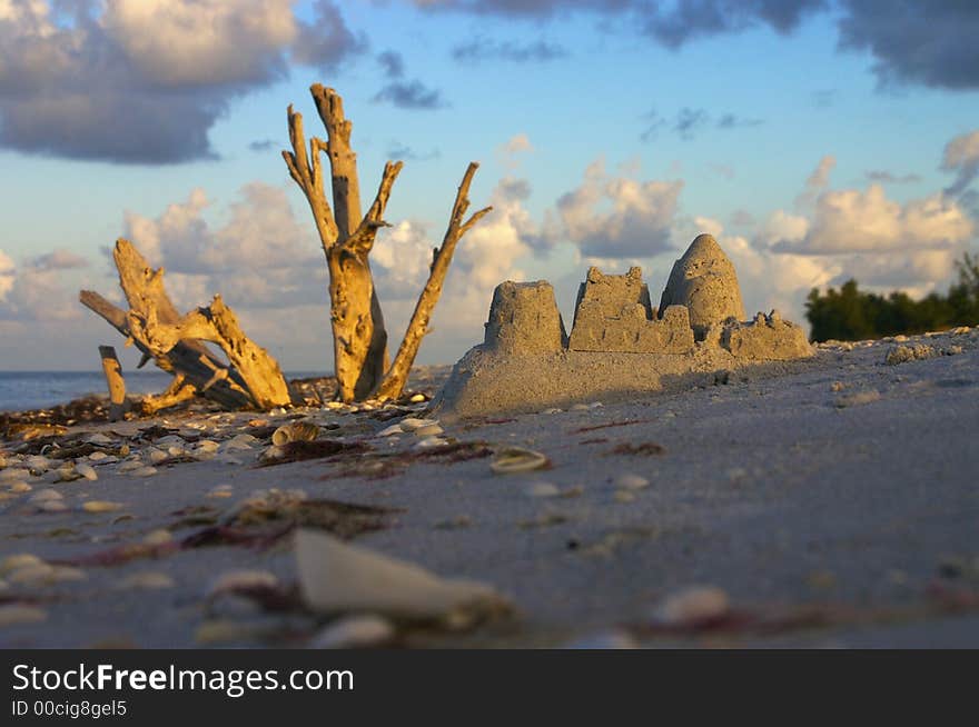 The early morning sun greets someone's leftover sandcastle - very low angle view. The early morning sun greets someone's leftover sandcastle - very low angle view