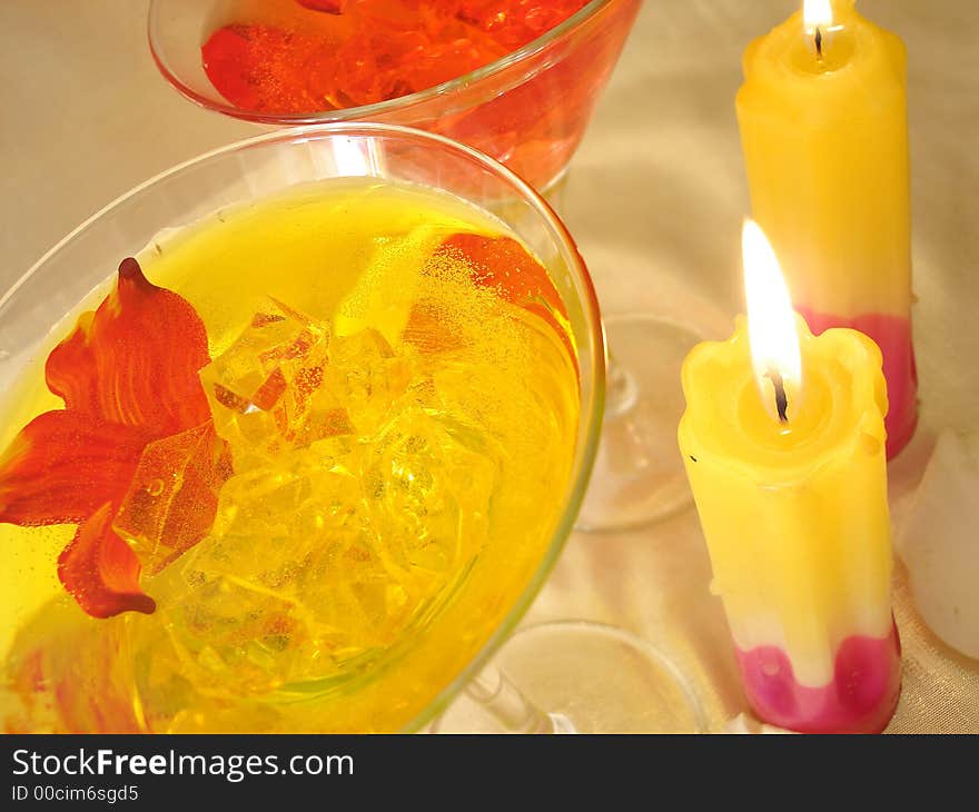 Yellow and red martini glasses with candles on golden background