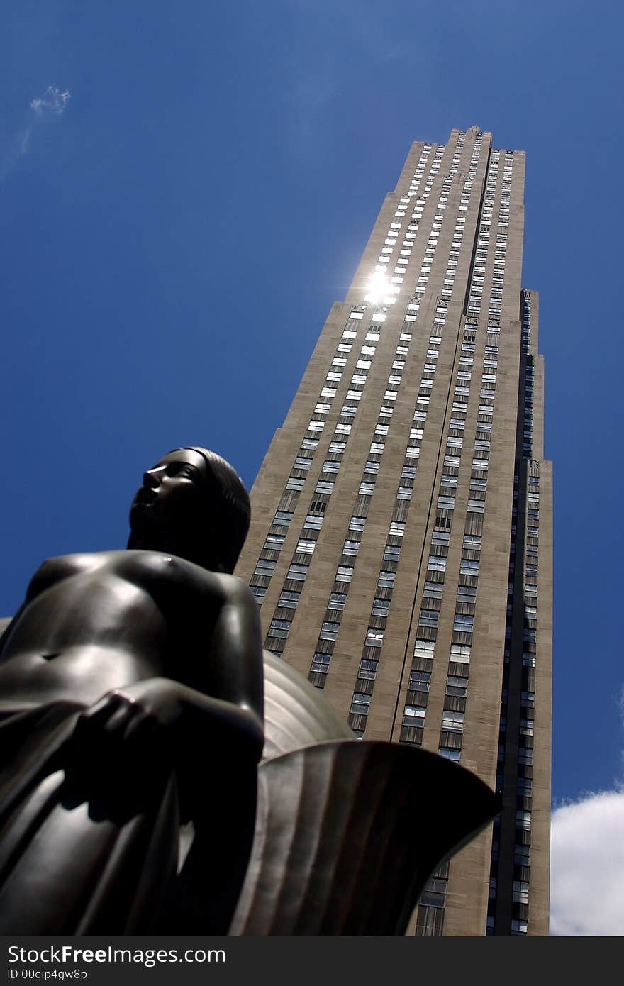 Partial view of a skyscraper with a monument infront in New York City by day, United States, America. Partial view of a skyscraper with a monument infront in New York City by day, United States, America