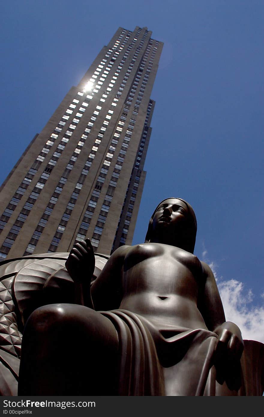 Partial view of a skyscraper with a monument infront in New York City by day, United States, America. Partial view of a skyscraper with a monument infront in New York City by day, United States, America