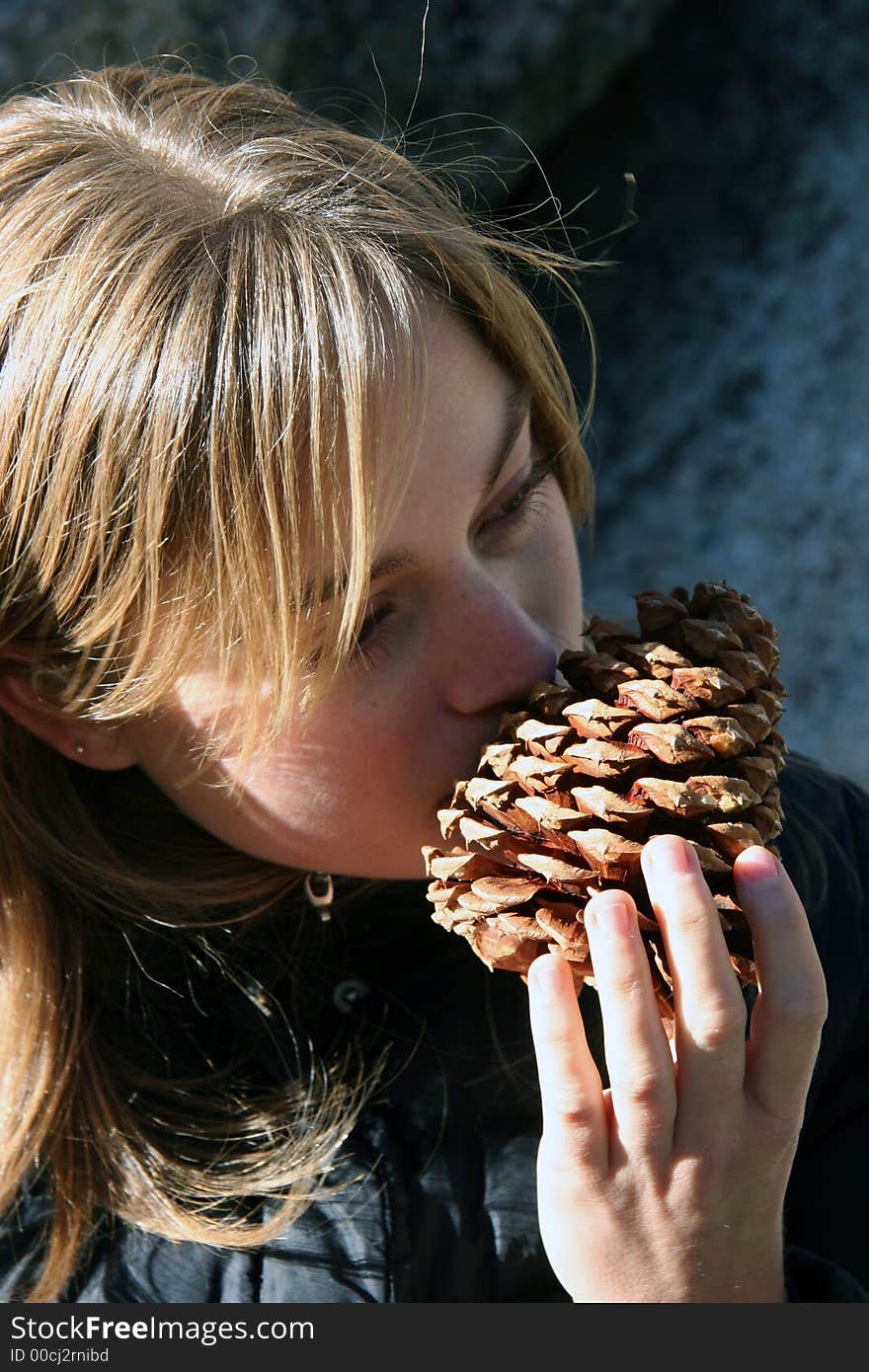 Young woman smelling a pine cone. Young woman smelling a pine cone