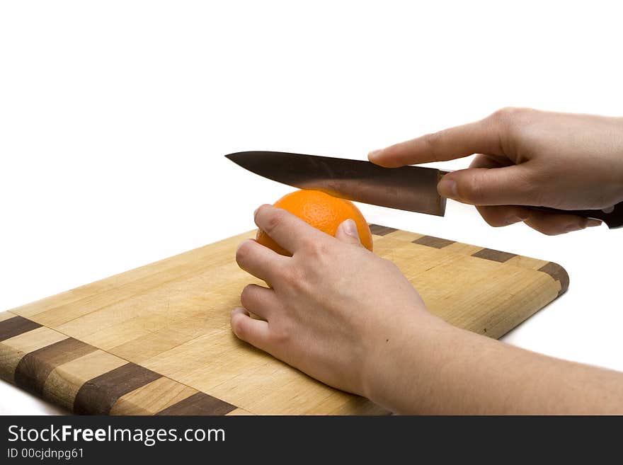 Cotting a orange with a kitchen's knife over a wooden table. Cotting a orange with a kitchen's knife over a wooden table