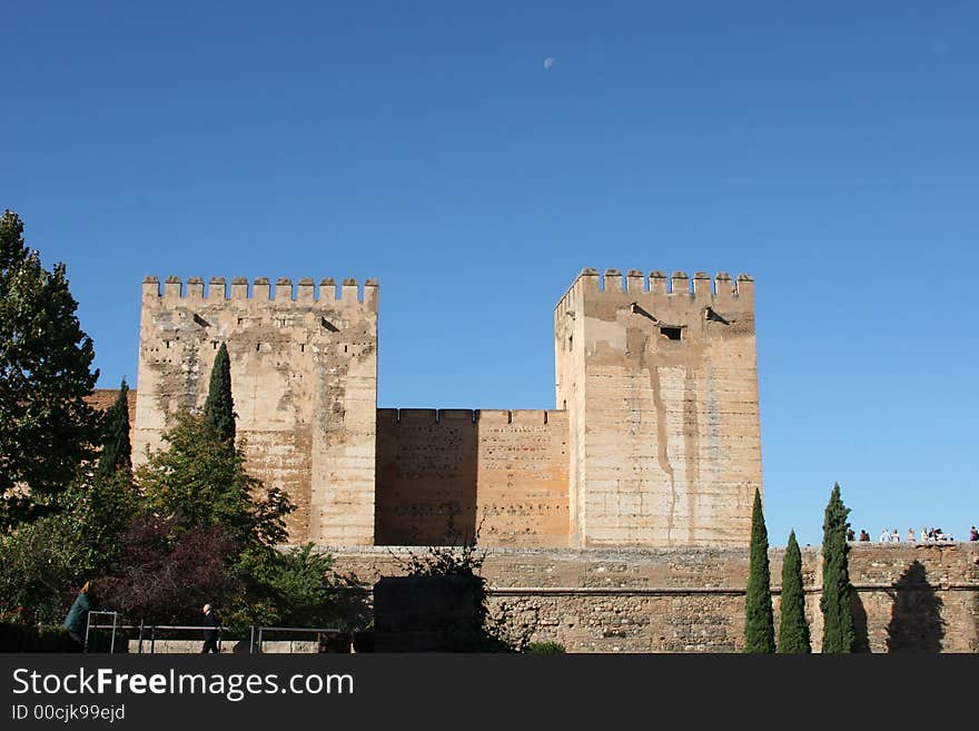 The Al Hambra, Grenada,Spain. Castle ramparts, garden and moon in the background. The Al Hambra, Grenada,Spain. Castle ramparts, garden and moon in the background