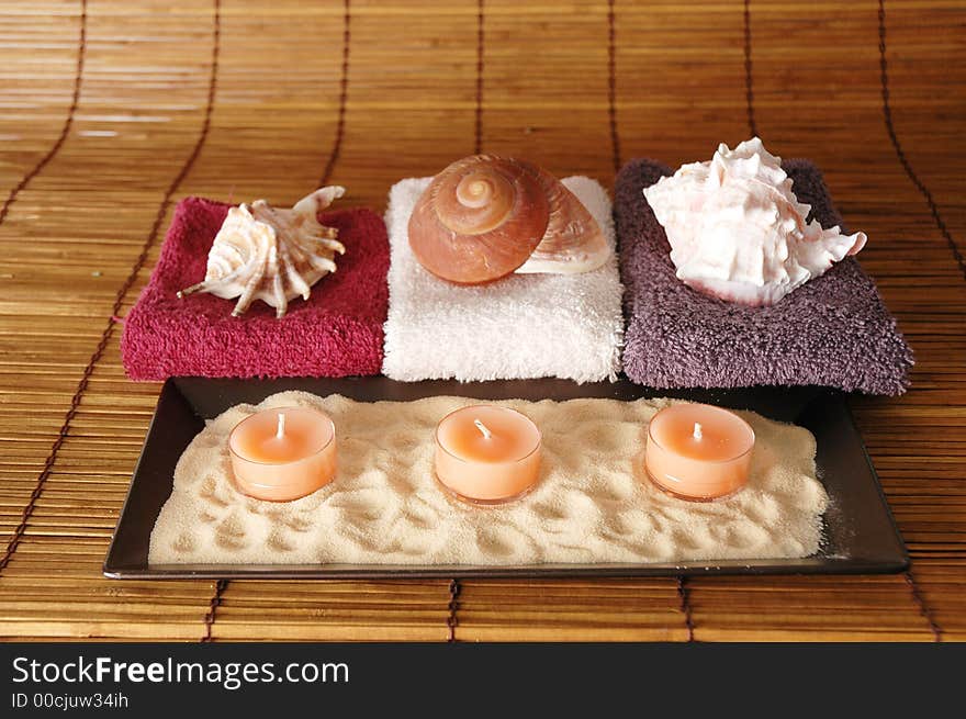 Sea shells, candle, sand positioned asa  beauty and relaxation concept. Sea shells, candle, sand positioned asa  beauty and relaxation concept