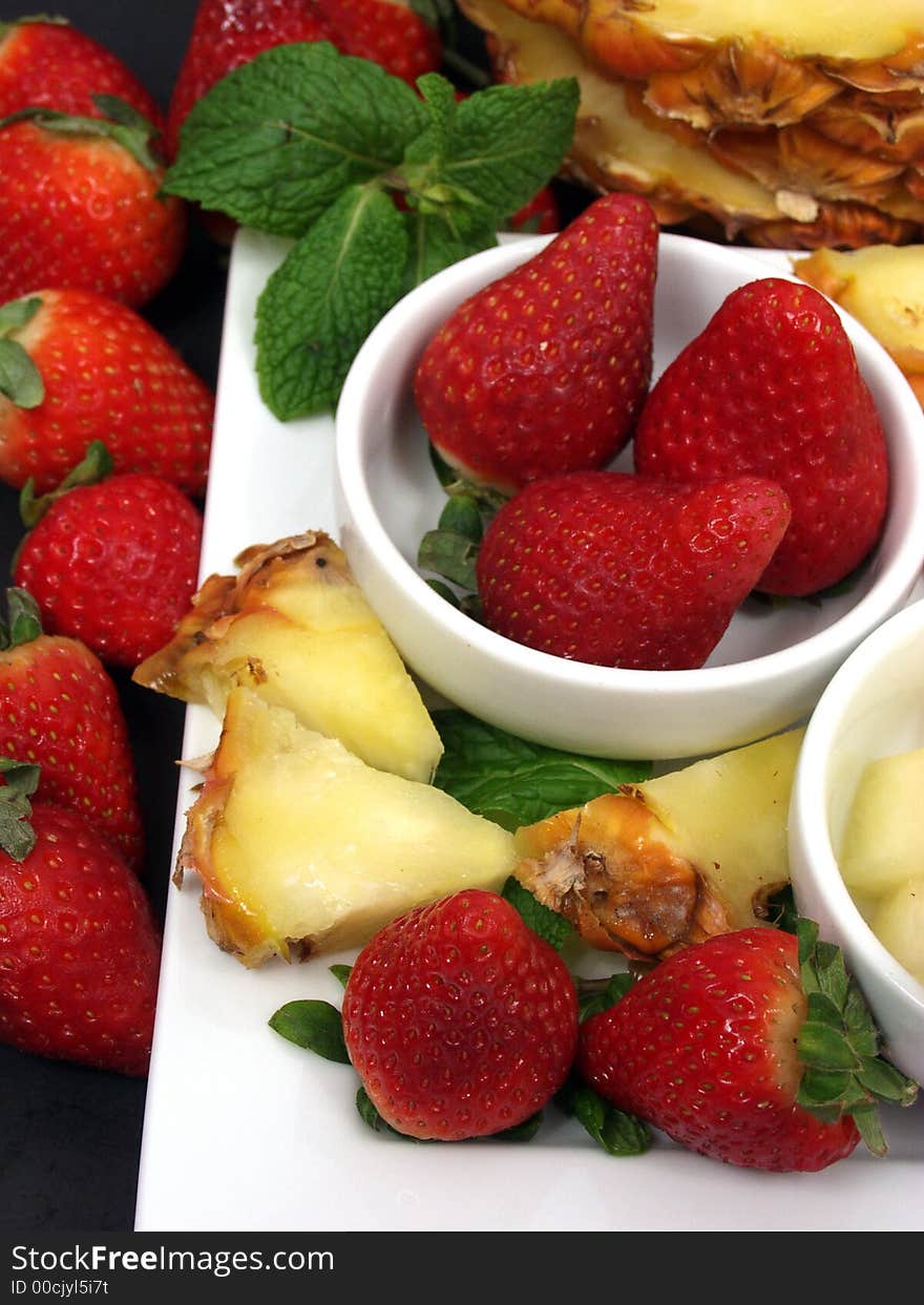 Fruit plate with strawberries and pineapple on black background. Fruit plate with strawberries and pineapple on black background