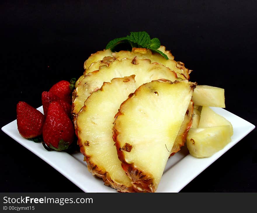 Fruit plate with strawberries and pineapple on black background. Fruit plate with strawberries and pineapple on black background