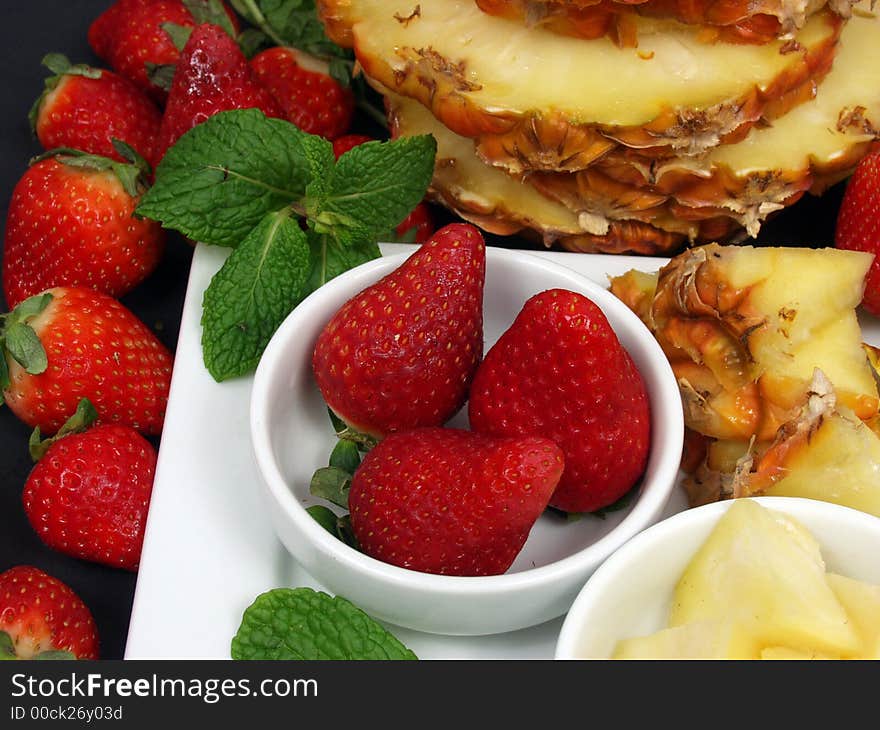 Fruit plate with strawberries and pineapple on black background. Fruit plate with strawberries and pineapple on black background