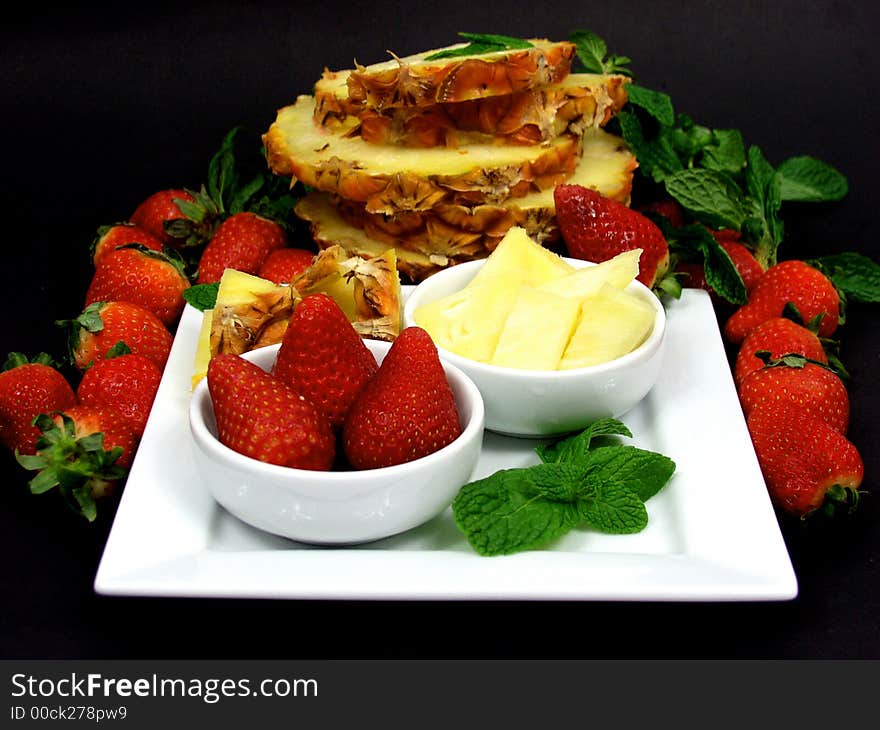 Fruit plate with strawberries and pineapple on black background. Fruit plate with strawberries and pineapple on black background