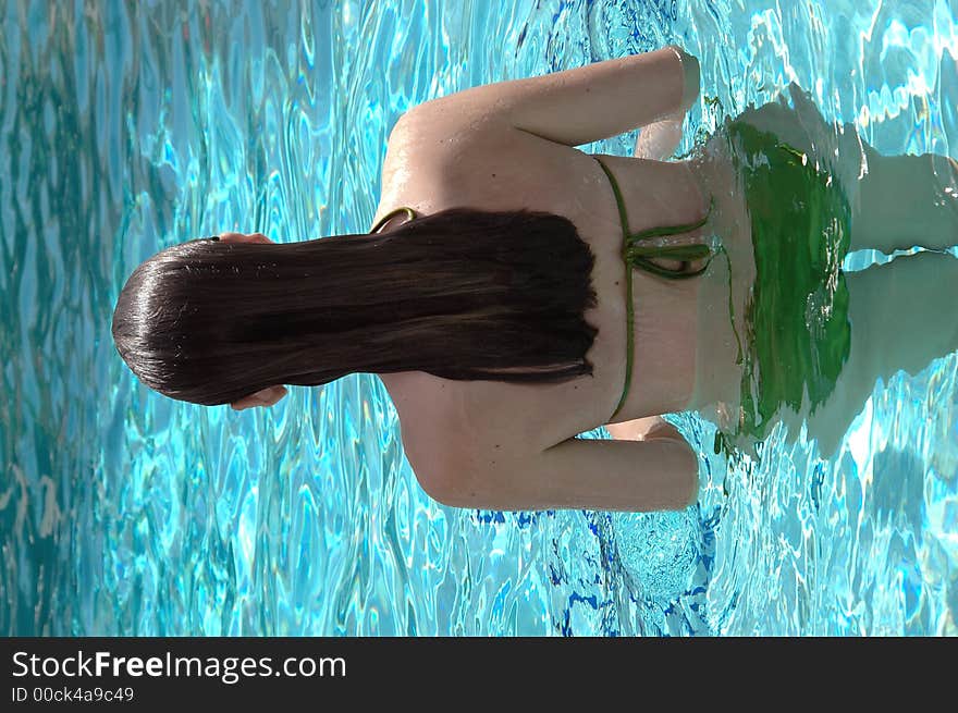 The back of a girl in the pool with long wet hair. The back of a girl in the pool with long wet hair