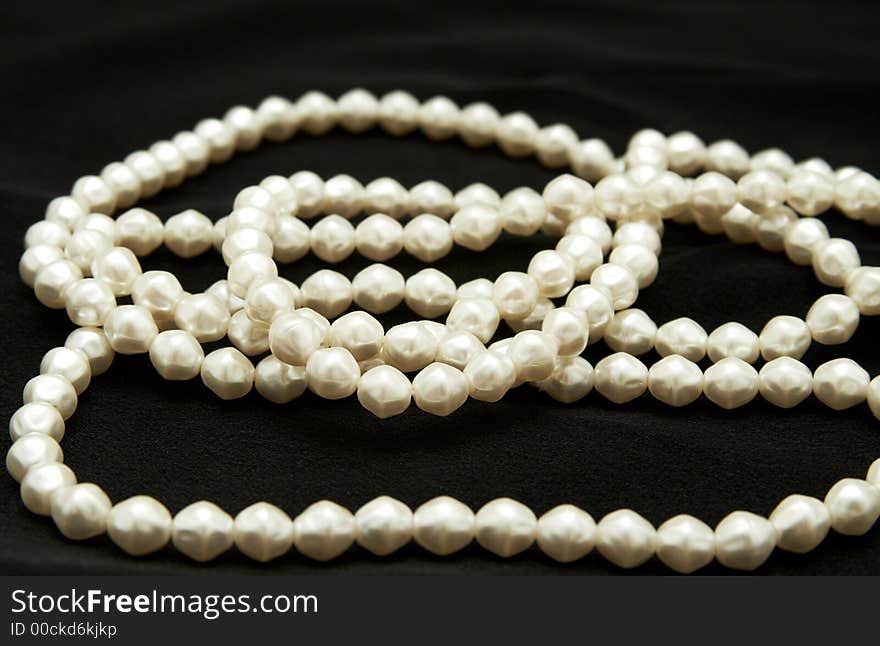 White real pearls on black velvet material background. White real pearls on black velvet material background.