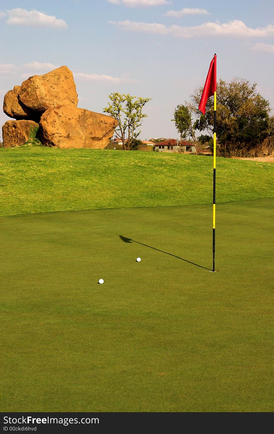 Red flag with two balls lying next to it on the green. Red flag with two balls lying next to it on the green.