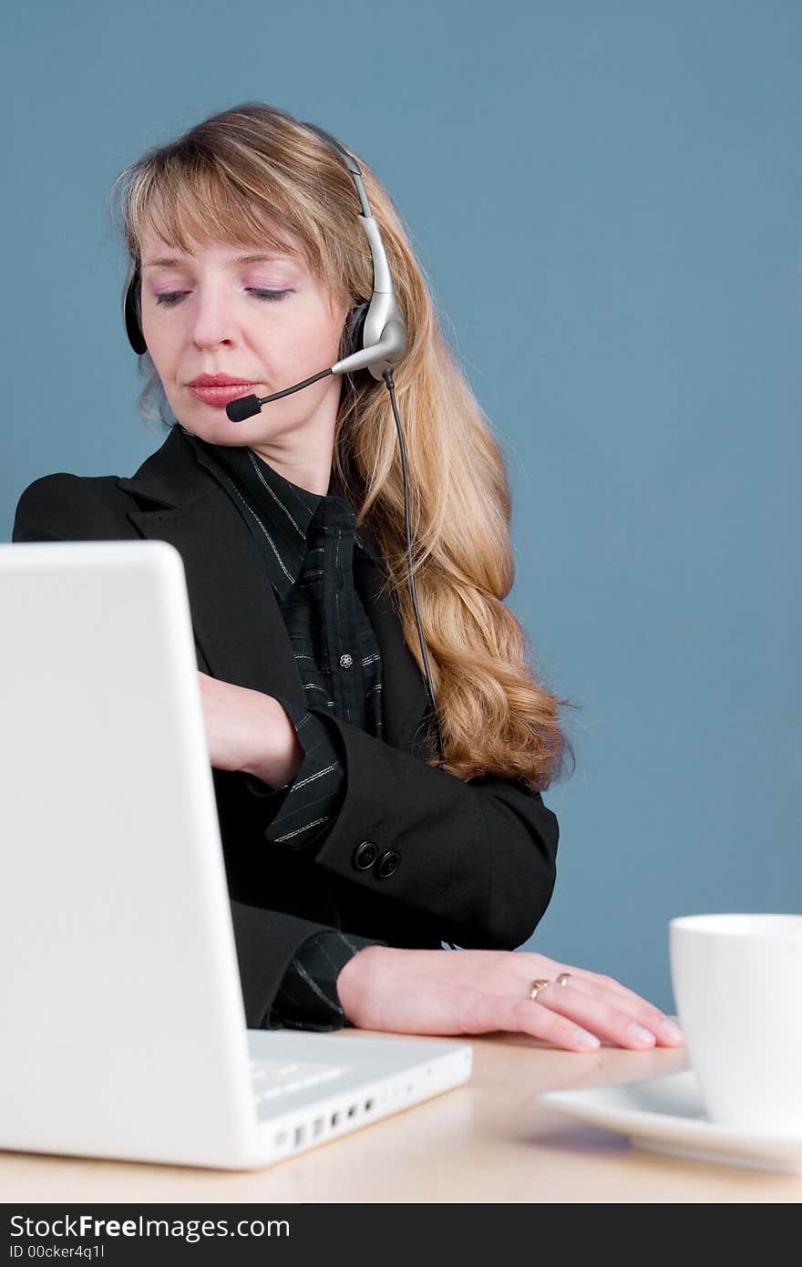 An annoyed customer service agent with a cup of coffee and a white computer. An annoyed customer service agent with a cup of coffee and a white computer