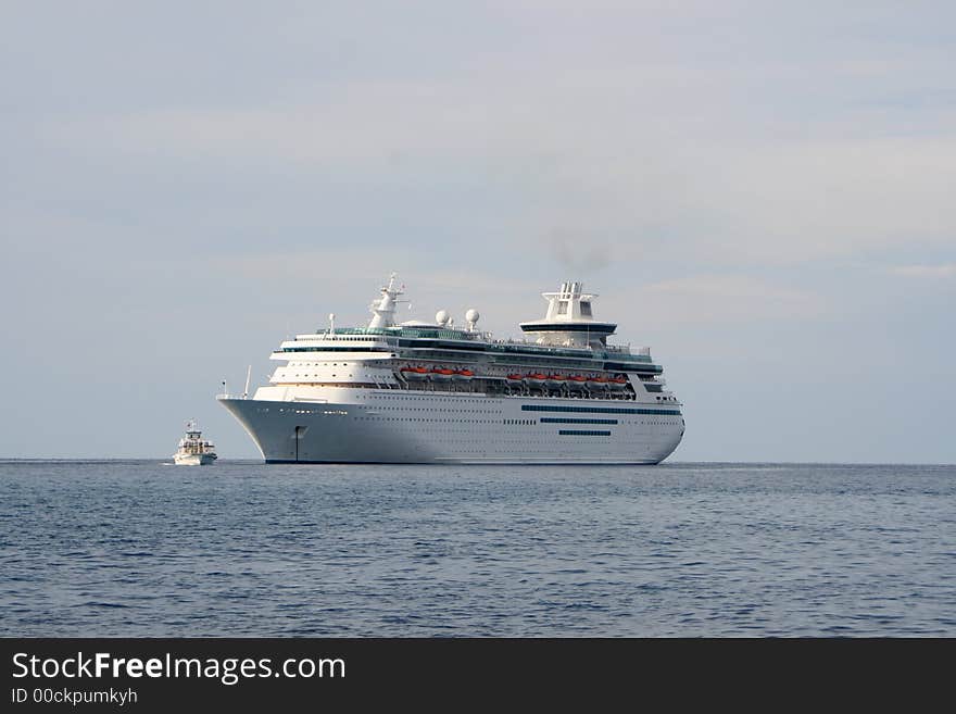 Small ferry carrying people to and from a large cruise ship in the ocean. Small ferry carrying people to and from a large cruise ship in the ocean.