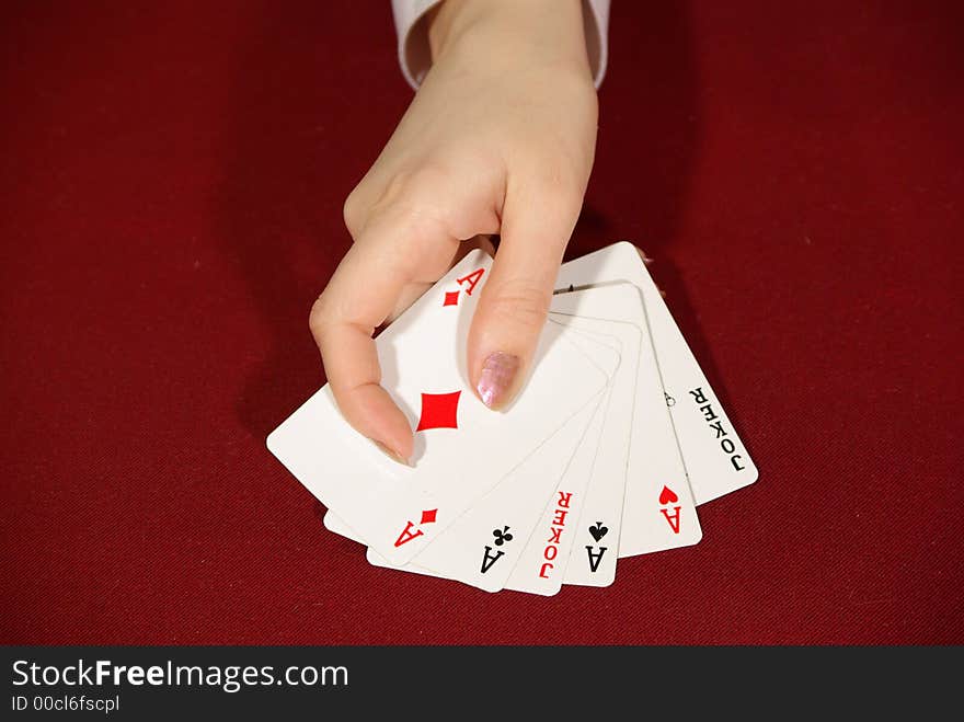 Two jokers and four aces - playing cards on red in human hand. Two jokers and four aces - playing cards on red in human hand