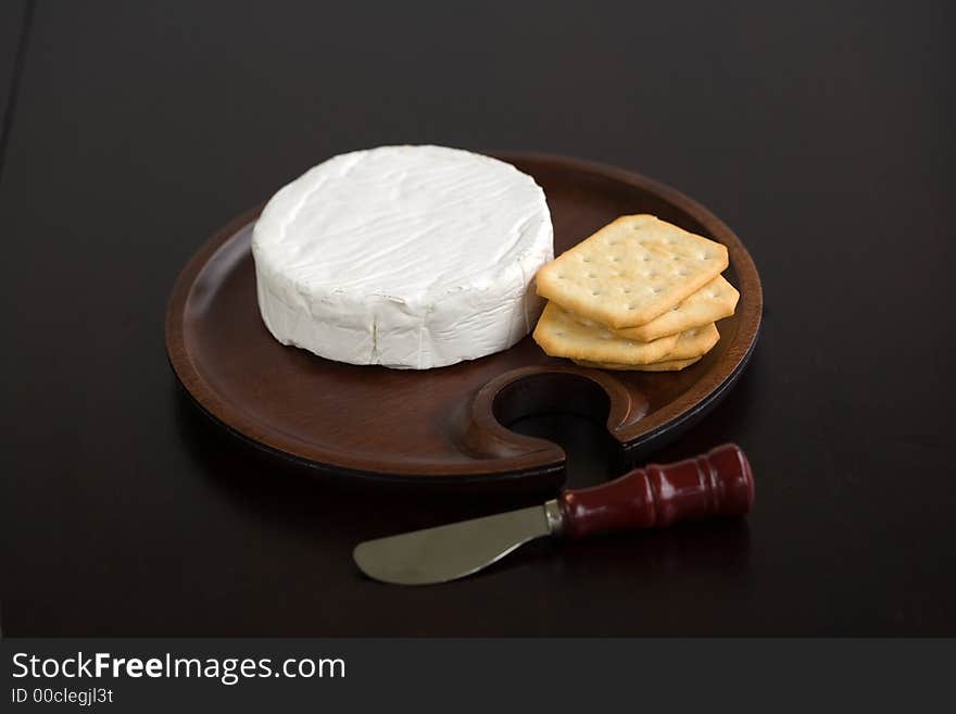 Brie and butter cracker on a wooden cheese plate with cheese knife. Brie and butter cracker on a wooden cheese plate with cheese knife