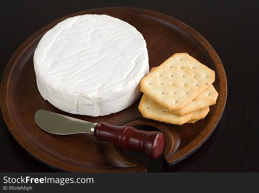 Brie and butter cracker on a wooden cheese plate with cheese knife. Brie and butter cracker on a wooden cheese plate with cheese knife