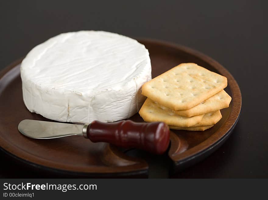 Brie and butter cracker on a wooden cheese plate with cheese knife. Brie and butter cracker on a wooden cheese plate with cheese knife