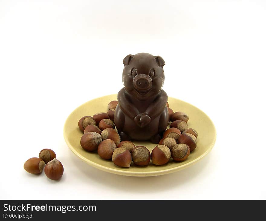 Chocolate a pig in a plate and nuts on a white background. Chocolate a pig in a plate and nuts on a white background