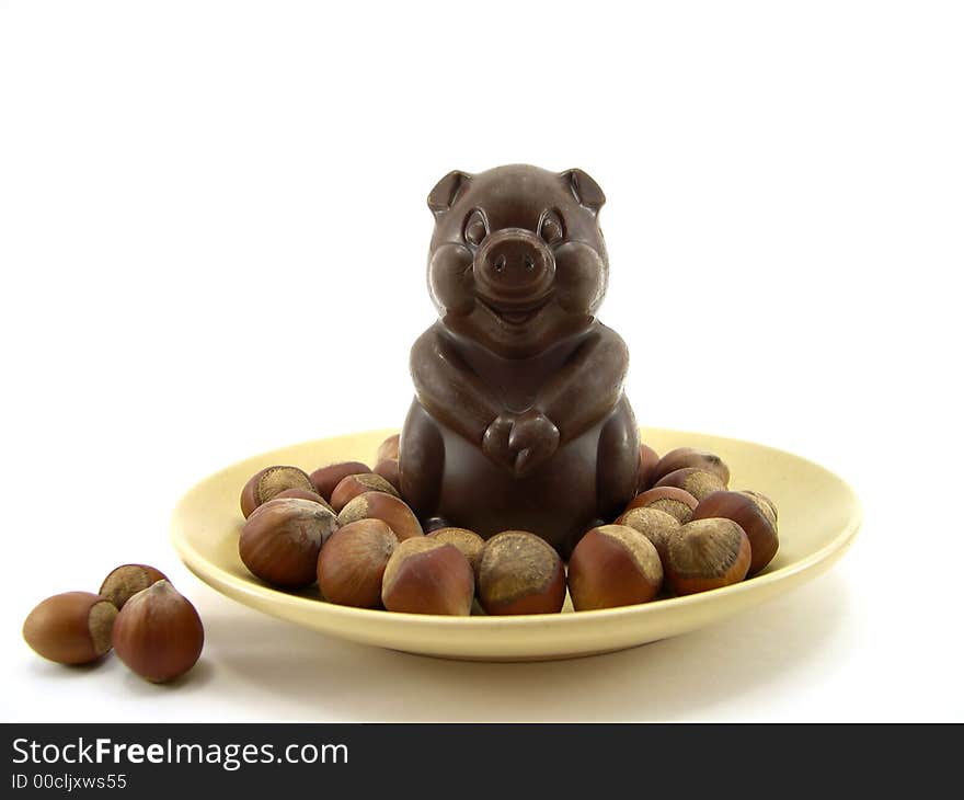 Chocolate a pig in a plate and nuts on a white background. Chocolate a pig in a plate and nuts on a white background