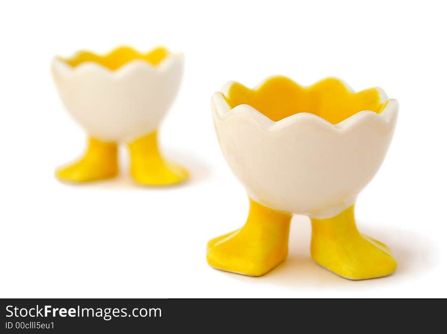 Two empty, funny egg holders waiting for their eggs. Shallow DOF with focus on the front of the front eggcup. Isolated on white background. Two empty, funny egg holders waiting for their eggs. Shallow DOF with focus on the front of the front eggcup. Isolated on white background.