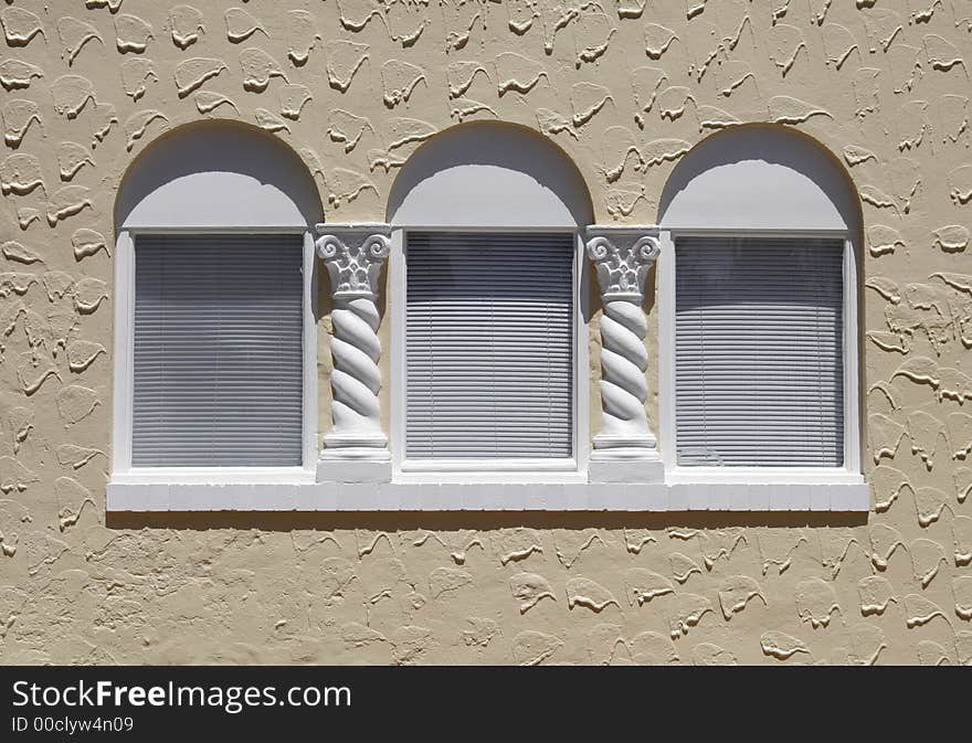 Three Windows With White Venetian Blinds On A Brown, Beige, Yellow Painted Wall
