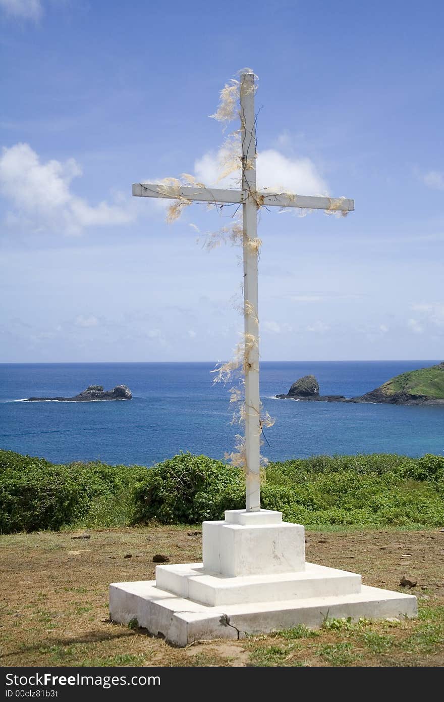 A simple white, wooden cross with the great blue ocean in the background!