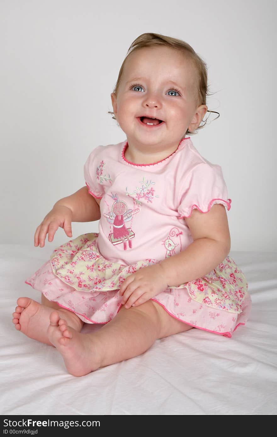 A little baby girl sitting in a pink dress. A little baby girl sitting in a pink dress