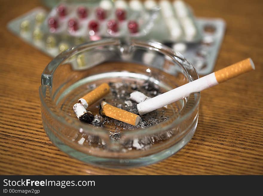 Cigarette, tablets and ashtray on a table, (studio, halogen light). Cigarette, tablets and ashtray on a table, (studio, halogen light).