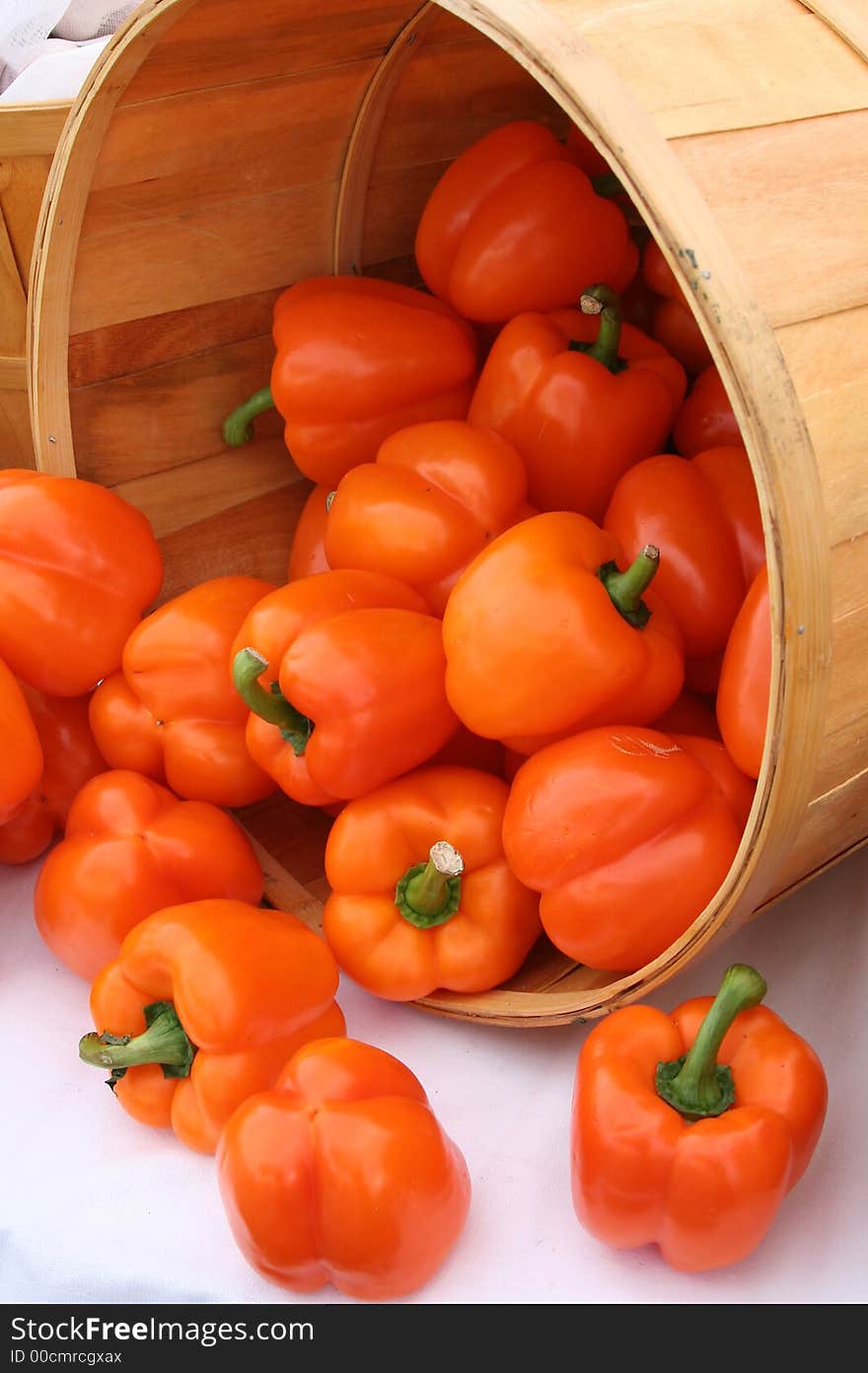 A basket of red peppers spilling out for a display at a farmers market