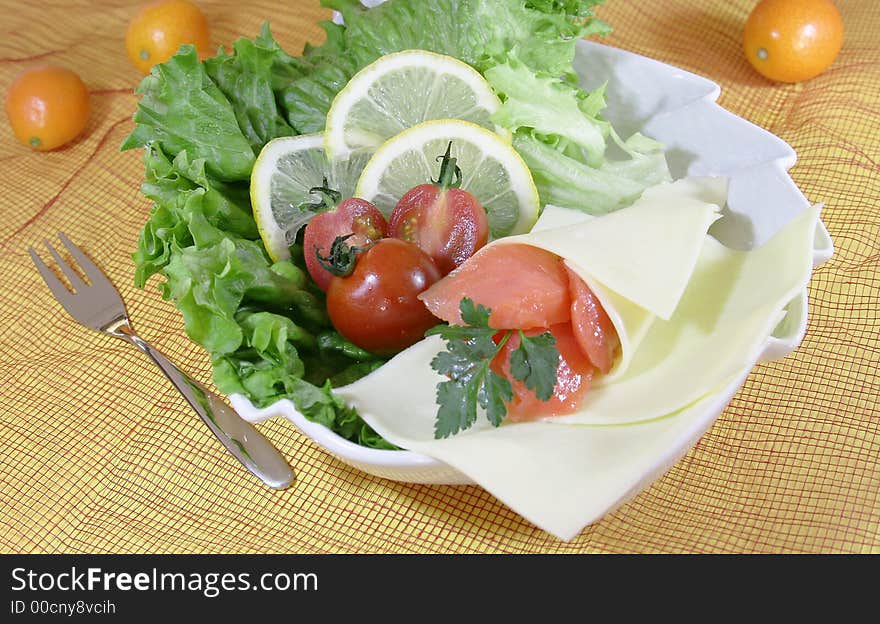 Closeup of fresh salad with cheese and lemon slice.