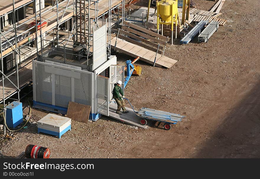 Construction worker pulling a cart into an elevator