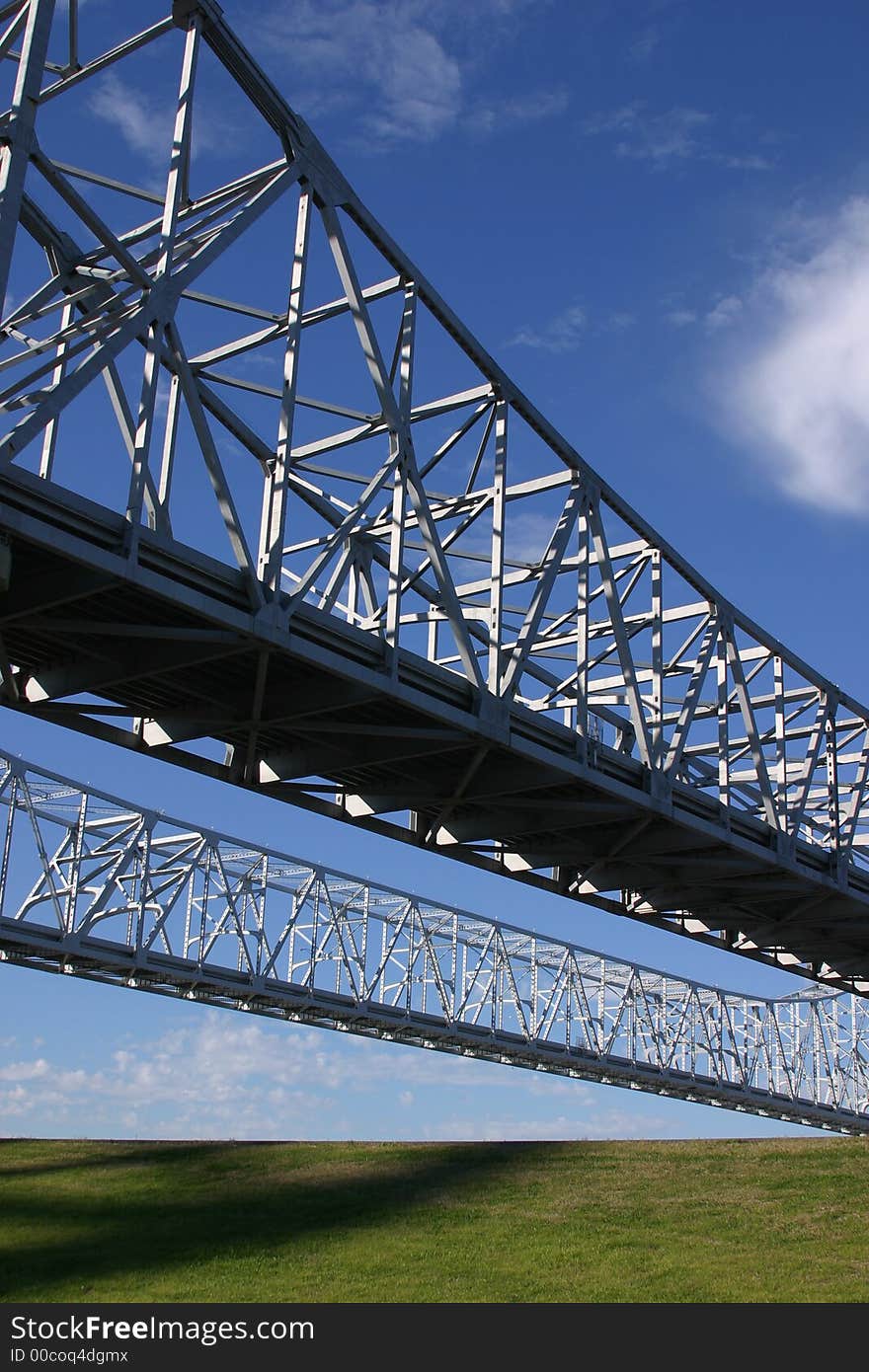 Twin bridge spans of the Crescent City Connection in New Orleans cross above a levee.