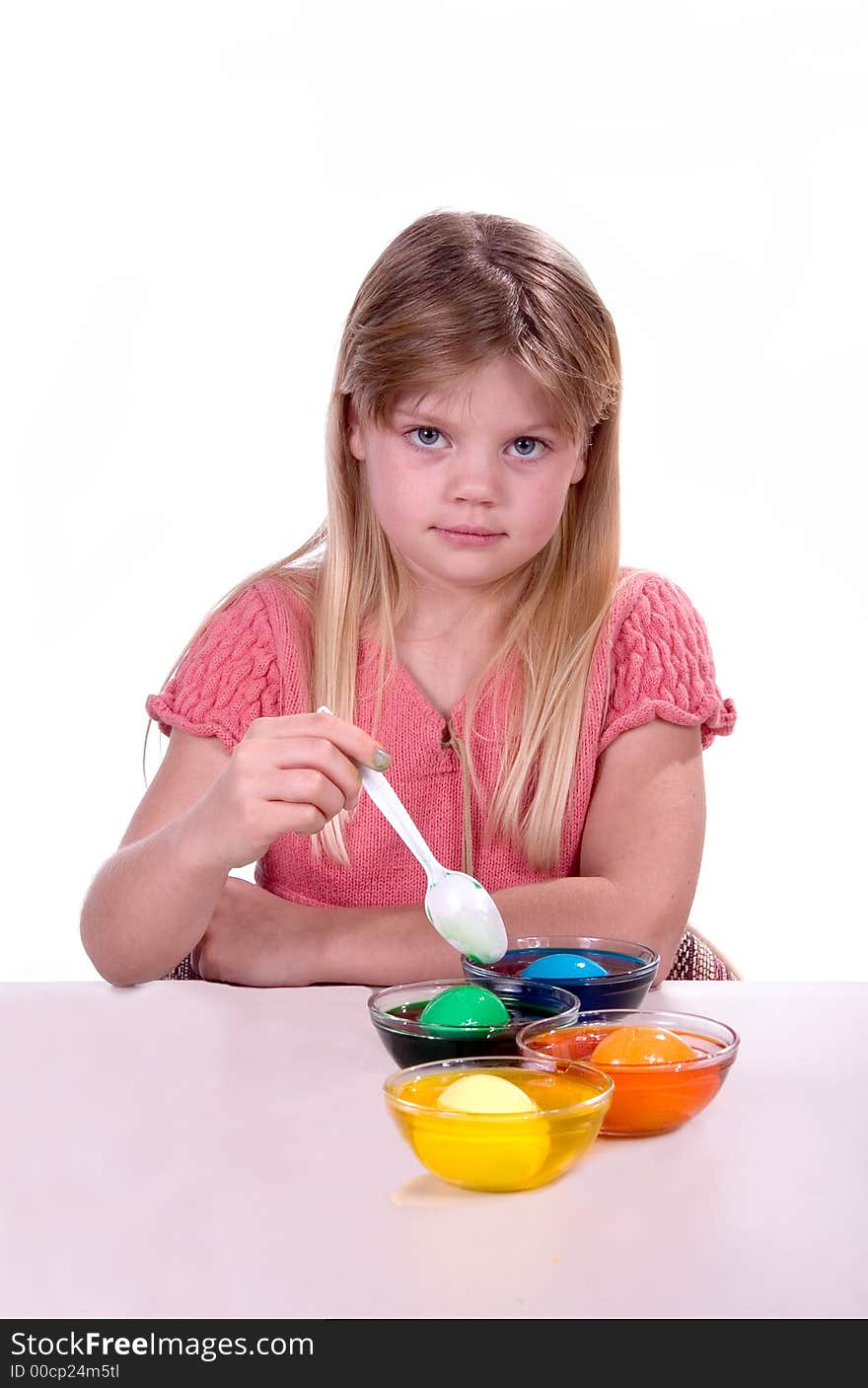 Young girl coloring easter eggs shot over white.