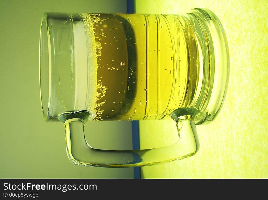 A glowing mug of beer on illuminated glass. A glowing mug of beer on illuminated glass