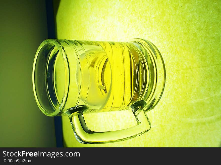 A glowing mug of beer on illuminated glass. A glowing mug of beer on illuminated glass