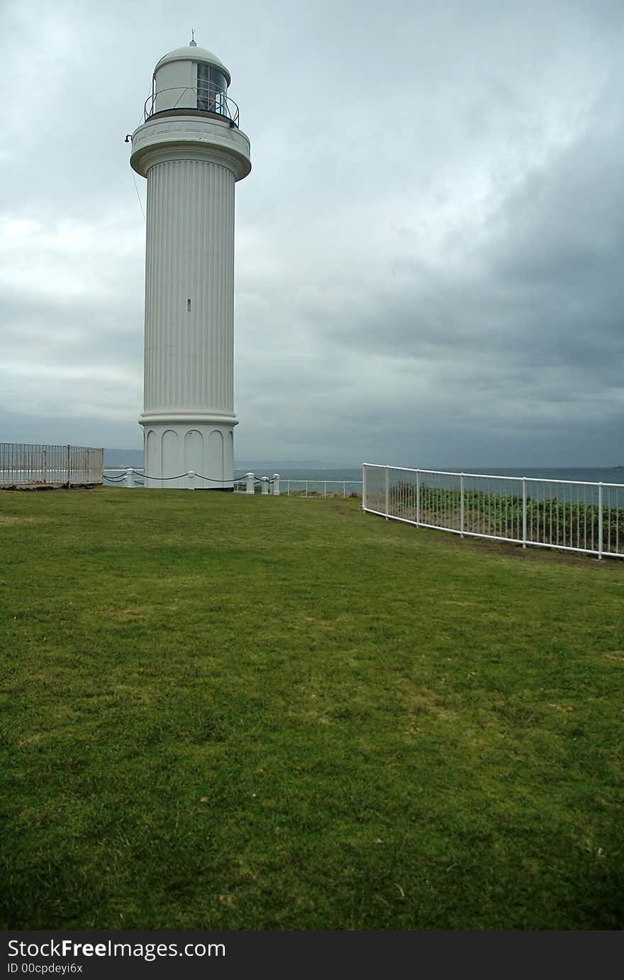 White lighthouse, dark grey sky, almost raining, coastline near sydney