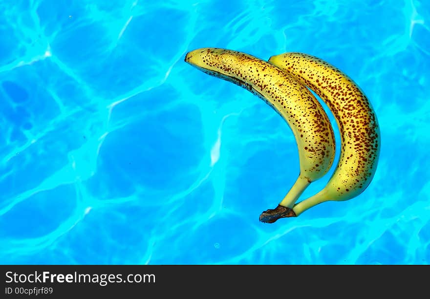 Two ripe bananas floating in a pool. Two ripe bananas floating in a pool